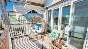 En overdækket terrasse med fletningsmøbler, en polstret stol og et lille bord.