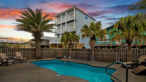 A swimming pool with lounge chairs and a wooden fence.