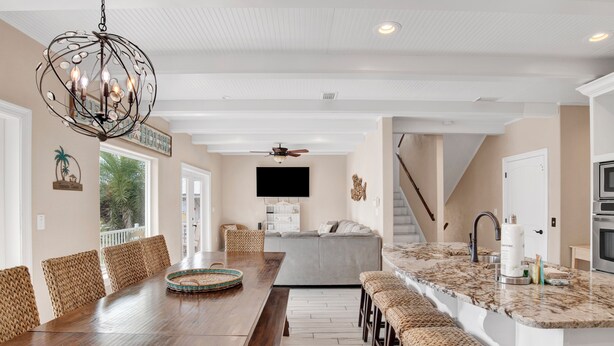 A spacious dining area with a long wooden table, wicker chairs, and a chandelier.