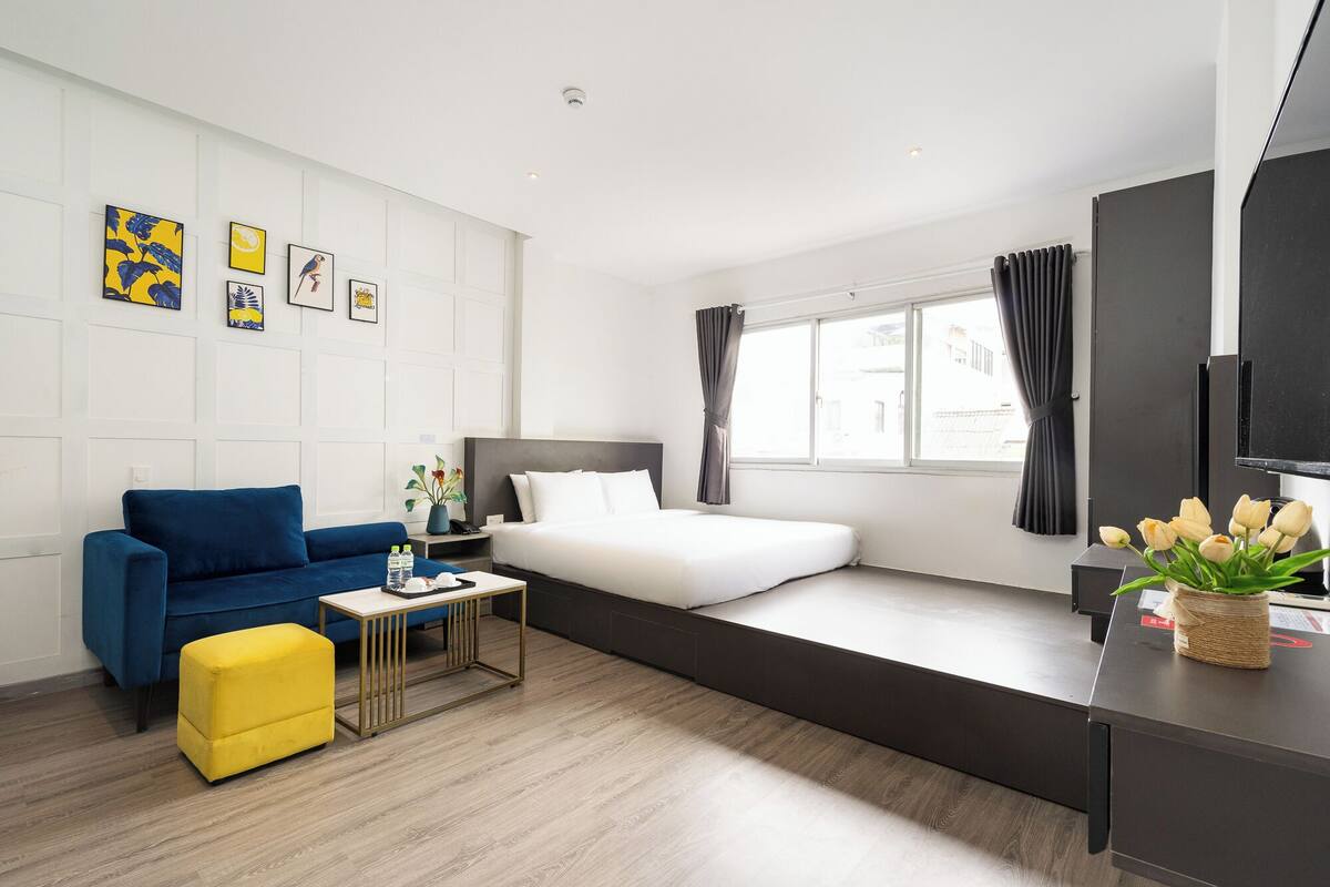 Une chambre d’hôtel moderne équipée d’un lit, d’un canapé, d’une petite table et d’un téléviseur.