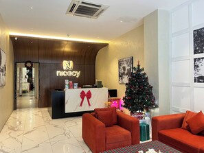 Eine Hotelrezeption mit Weihnachtsbaum, roten Sofas und einem Marmorboden.