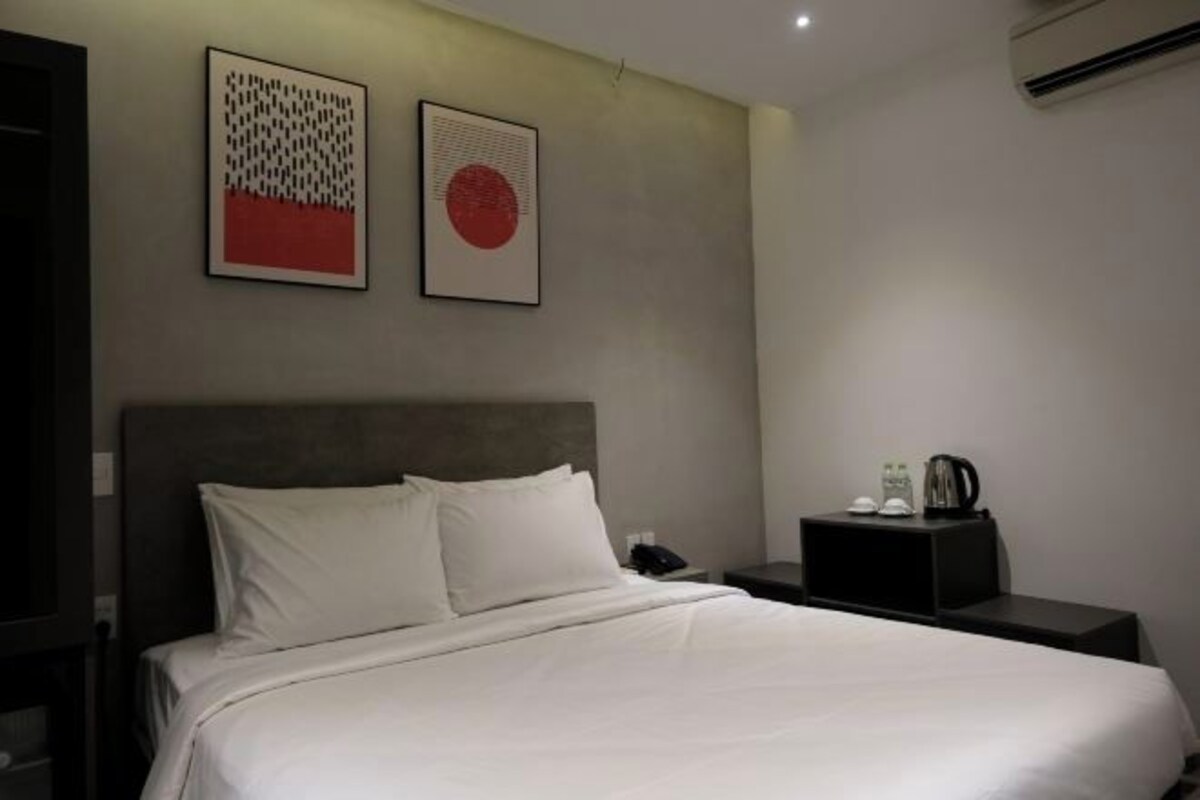 Habitación de hotel con cama, una mesita de noche y dos obras de arte colgadas en la pared.