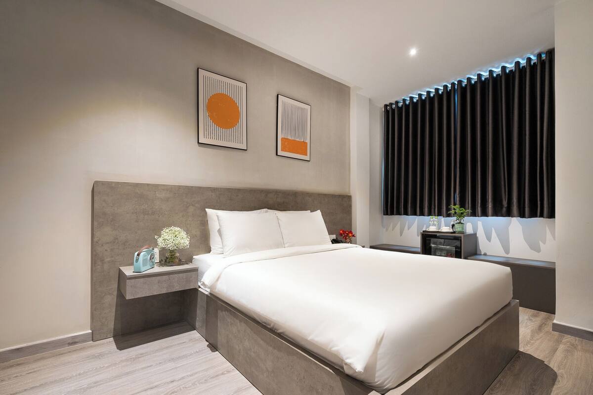Une chambre moderne avec un grand lit, une table de chevet, une commode et une fenêtre avec des rideaux.