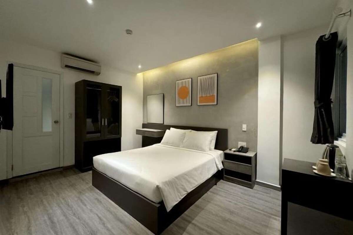 Una habitación de hotel moderna con una cama grande, una mesita de noche y un armario.