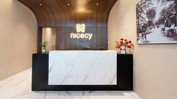 A reception desk with a marble top, a wooden ceiling, and a neon sign.