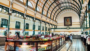 A spacious indoor market with a high arched ceiling and a central display area with various items for sale.
