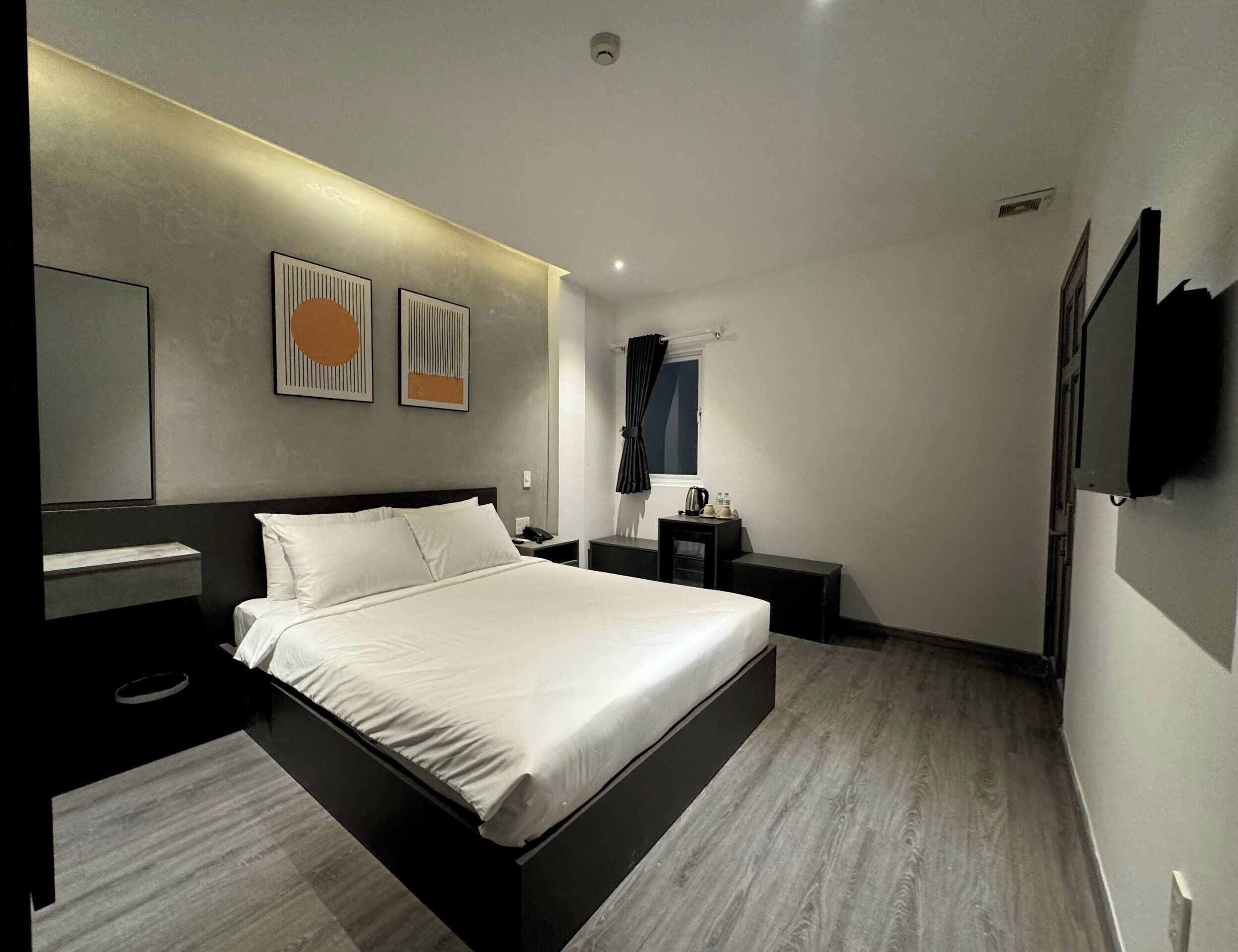 Habitació d'hotel moderna amb un llit gran, taules de nit, televisió de pantalla plana i obra d'art a les parets.