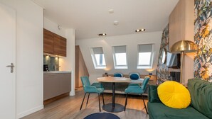 A modern living room with a green sofa, teal chairs, a round coffee table, and a dining area with a small table and chairs. - Cozy Couple's Escape (Zoutelande)