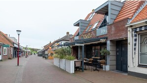 A street with a restaurant named 'OZieZo' featuring outdoor seating and a brick facade. - Cozy Couple's Escape (Zoutelande)