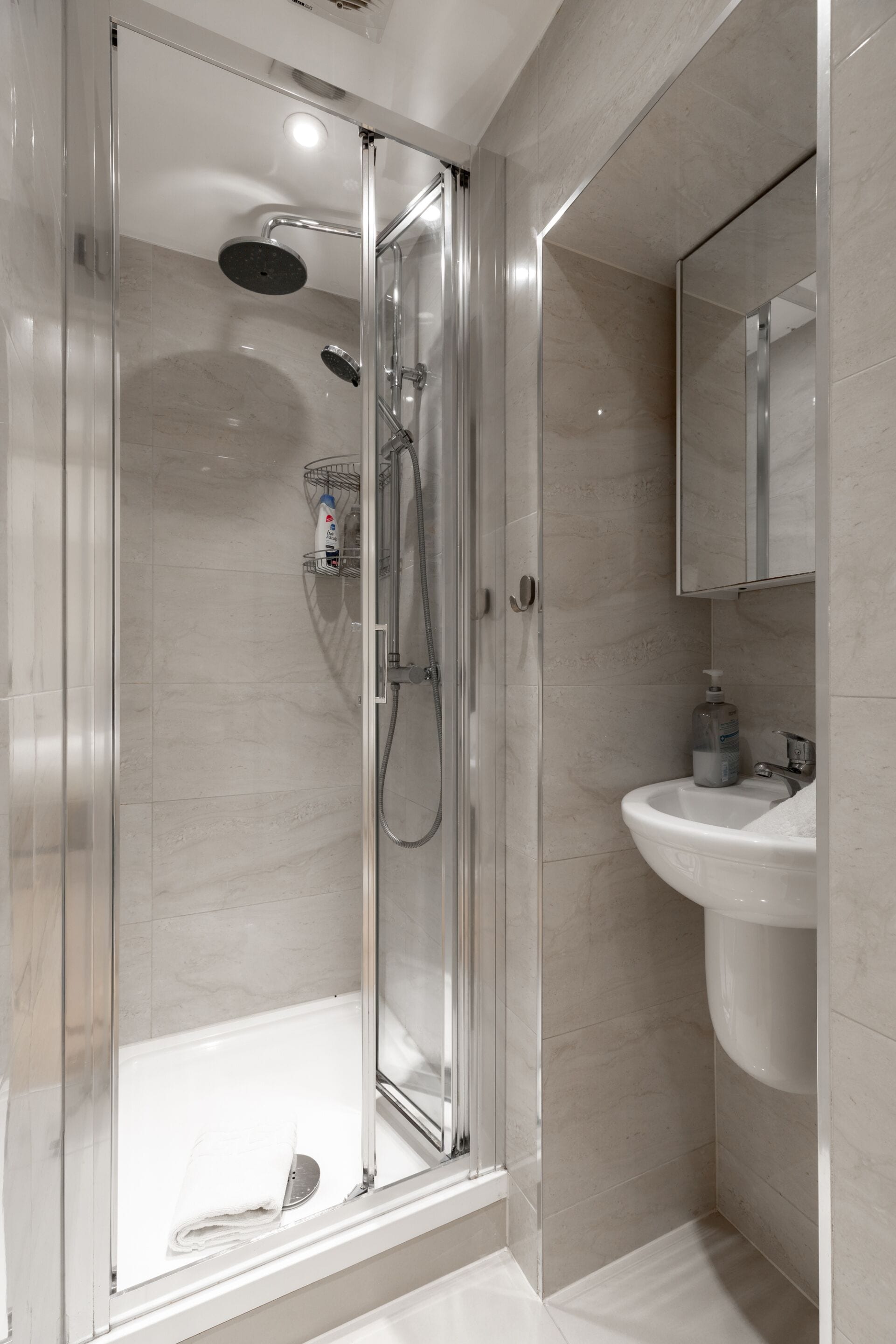 A modern bathroom with a glass-enclosed shower, a white sink, and a mirror above the sink.