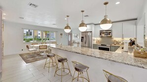 A modern kitchen with granite countertops, stainless steel appliances, and pendant lighting. - Poolside Paradise Dock & Pool! (Oakland Park)