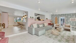 A modern living room with a sectional sofa, two armchairs, a dining area with a table and chairs, and a kitchen in the background. - Poolside Paradise Dock & Pool! (Oakland Park)