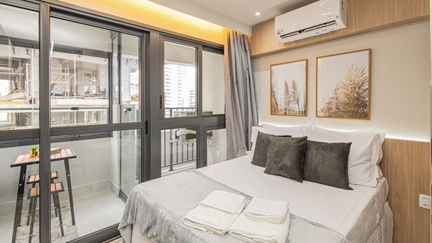 A modern hotel room with a large bed, a desk, and a balcony with a view of the city. - SSP - Soma Perdizes (São Paulo)