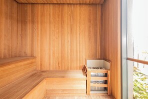 A wooden sauna with benches and a small table, a glass door, and a view of greenery outside. - SSP - Soma Perdizes (São Paulo)