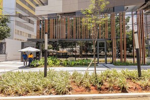 A modern building with a glass facade, a covered walkway, and a landscaped area with plants. - SSP - Soma Perdizes (São Paulo)