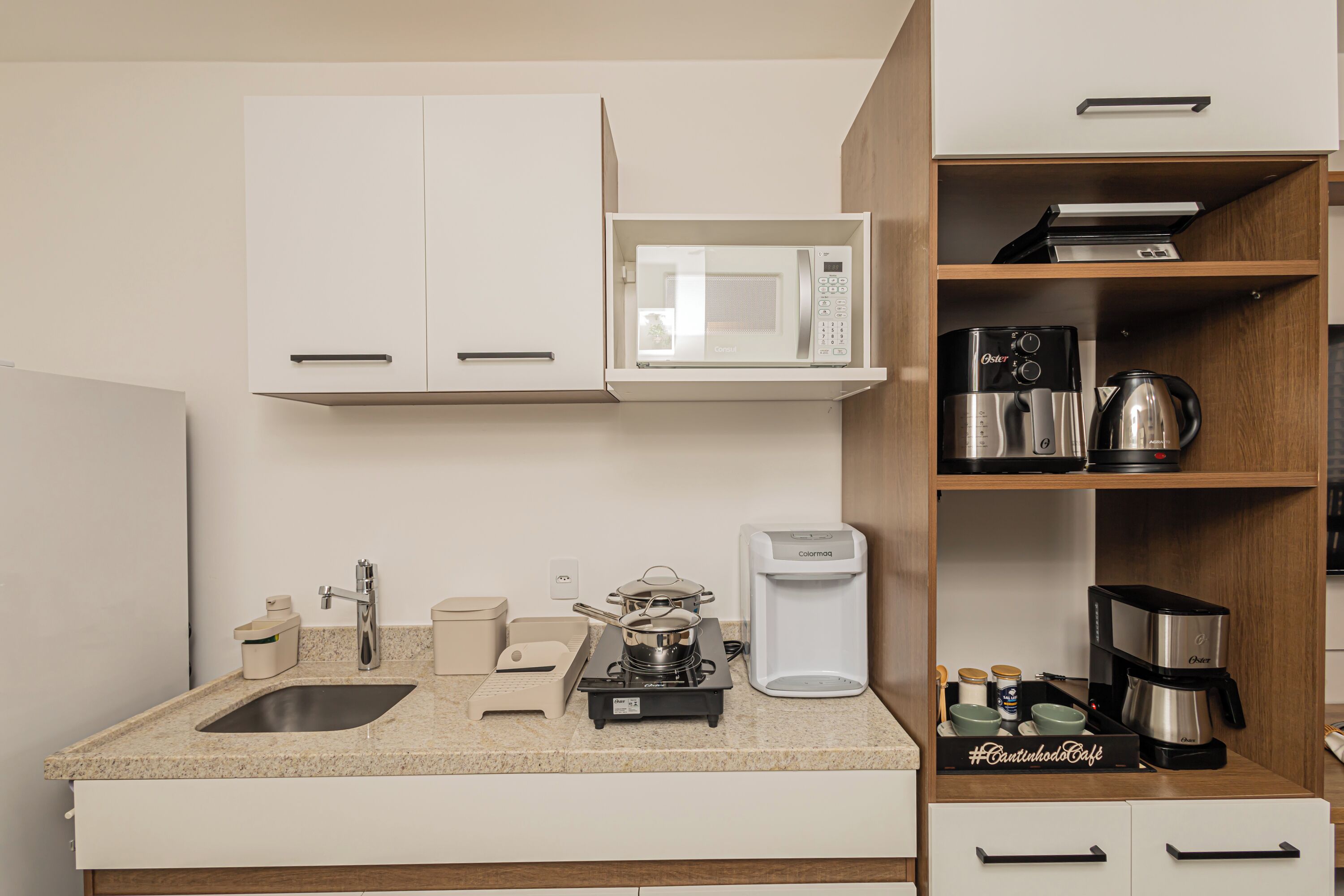 A compact kitchenette with a microwave, coffee maker, and electric kettle.