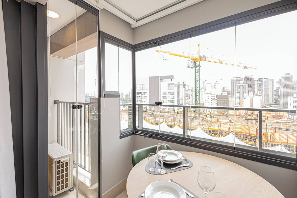 A room with a balcony overlooking a construction site and a cityscape.