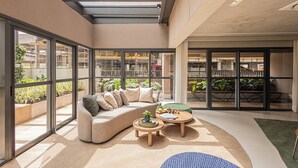 A modern interior with a curved sofa, two round tables, and a skylight. - SSP - Soma Perdizes (São Paulo)