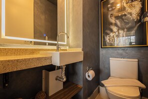 A bathroom with a granite countertop sink, a mirror, a toilet, and a framed artwork on the wall. - SSP - Soma Perdizes (São Paulo)