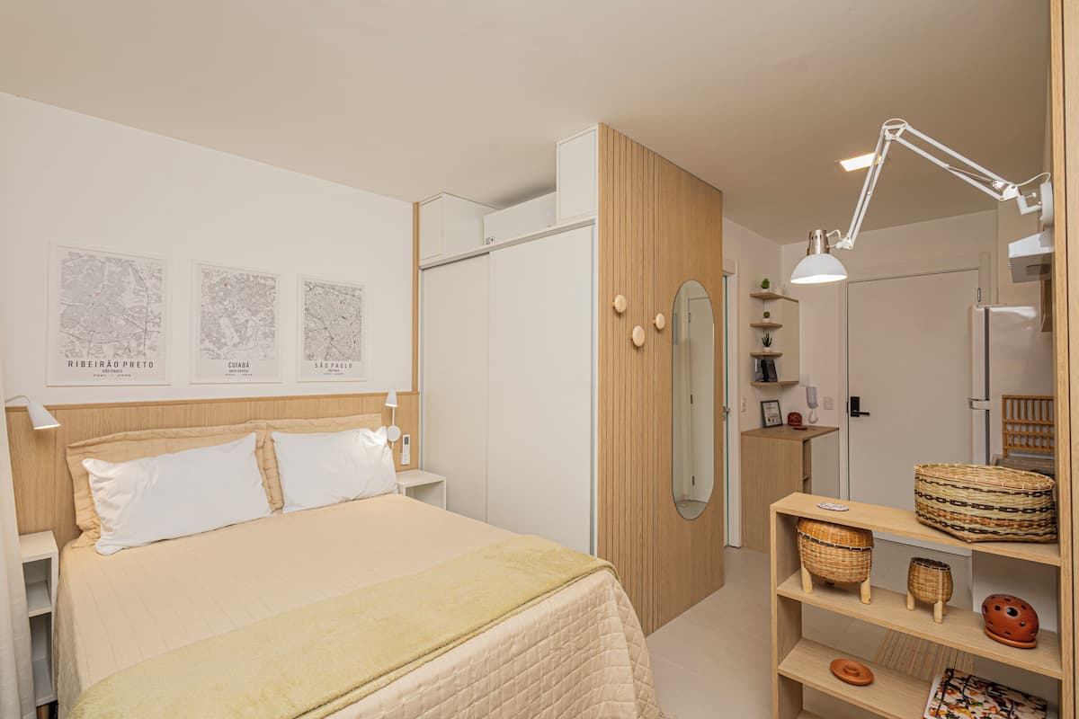 A bedroom with a bed, a wardrobe, a mirror, and a shelf with baskets.