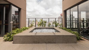A rooftop pool with a city view, surrounded by plants and modern architecture. - SSP - Soma Perdizes (São Paulo)