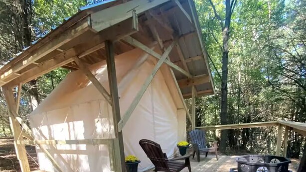 A wooden deck with a covered seating area, a table, and a fire pit.