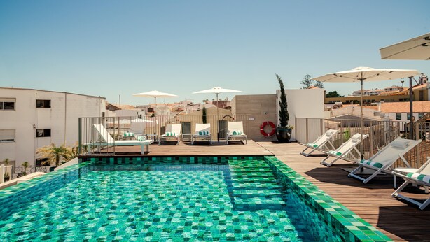 A rooftop pool with clear blue water, surrounded by lounge chairs and umbrellas. - The MN56 Hotel (Lagos)