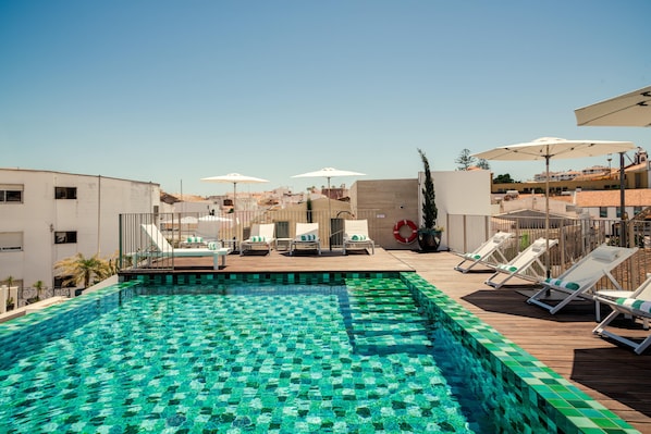 Een buitenzwembad, parasols bij het zwembad en ligstoelen