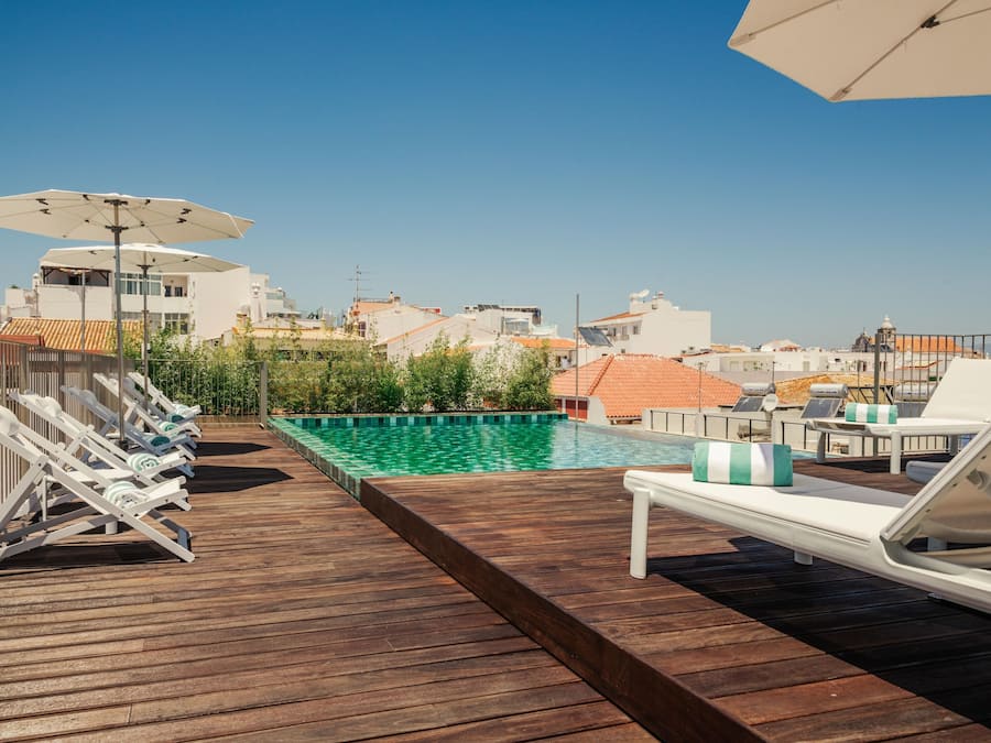 Alberca al aire libre, sombrillas en la alberca y camastros