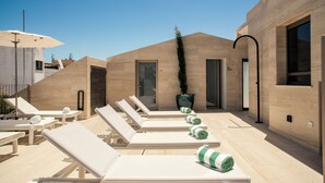 A rooftop lounge area with sun loungers, a potted plant, and a clear blue sky. - The MN56 Hotel (Lagos)