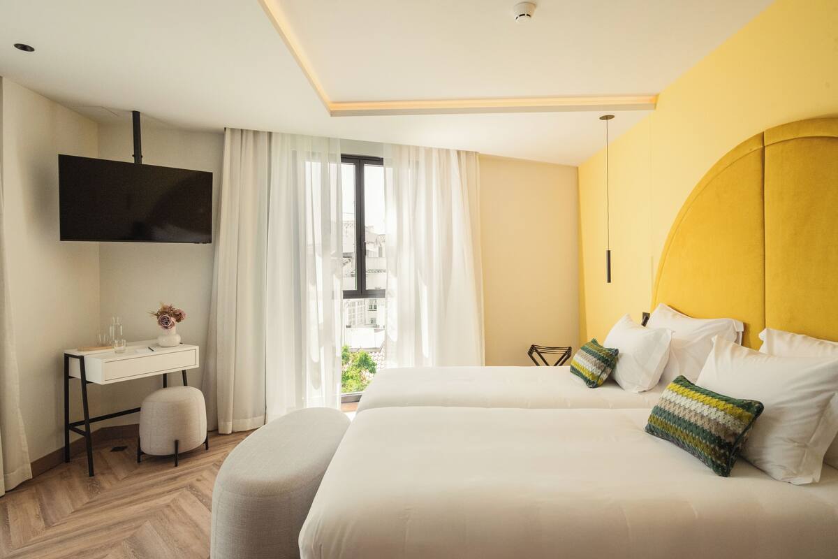 Une chambre d’hôtel avec un lit, un bureau, une télévision et une fenêtre avec des rideaux.
