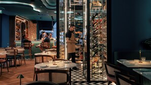 A restaurant interior with round tables, chairs, and a wine rack. - The MN56 Hotel (Lagos)