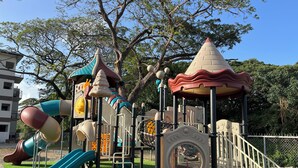 Un parque infantil con toboganes, estructuras para escalar y una casita.