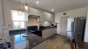 Una cocina moderna con una isla central, electrodomésticos de acero inoxidable e iluminación colgante.