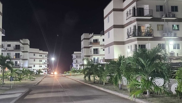 Un complejo residencial nocturno con varios pisos, balcones y unidades de aire acondicionado.