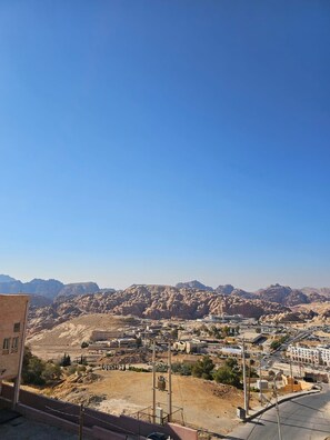A desert landscape with rocky mountains in the background and a town with buildings and roads in the foreground. - Summit Hotel (Wadi Musa)