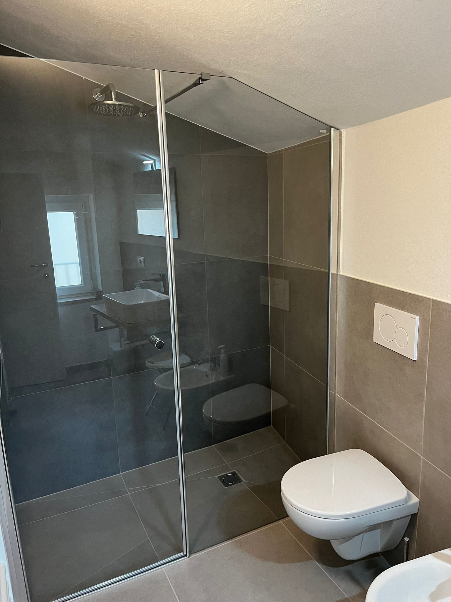 A modern bathroom with a glass-enclosed shower, a toilet, and a sink.