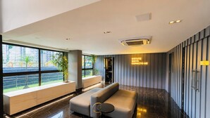 Eine moderne Lobby mit einer Couch, einem Empfangstisch und einem großen Fenster mit Blick ins Freie.
