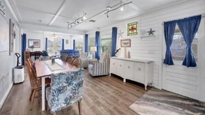A spacious living room with a wooden dining table, blue curtains, and a white cabinet.
