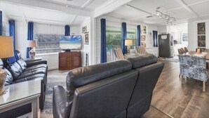 A spacious living area with a large sofa, a television, and a dining area with a table and chairs.
