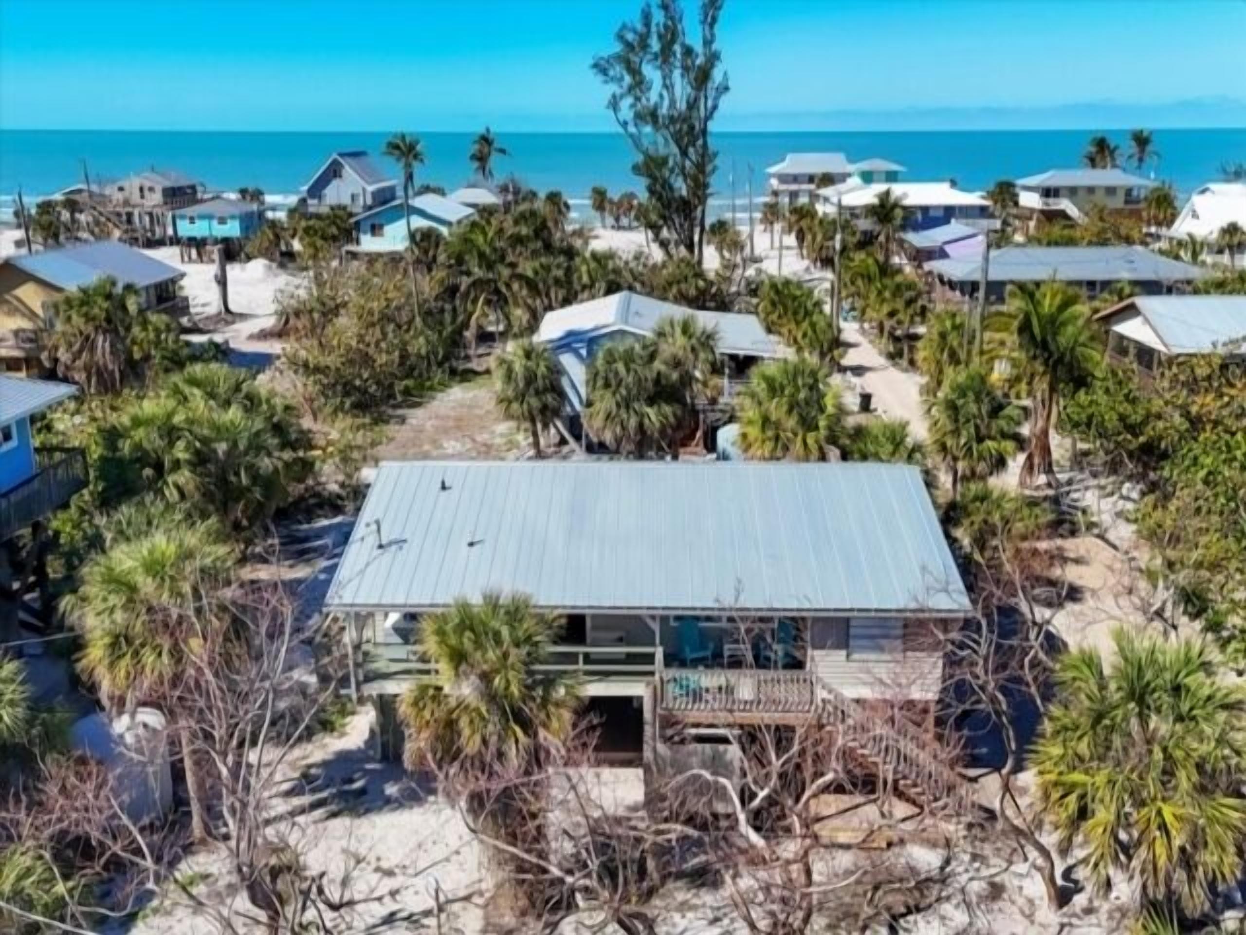 Uma área residencial à beira-mar, com casas cercadas por palmeiras e uma praia.
