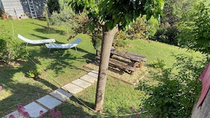 Un jardin avec un banc en bois, un hamac et un arbre.