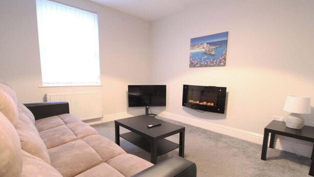 A living room with a sofa, two flat-screen TVs, a fireplace, and a painting on the wall. - Fishermans View Summa (Fleetwood)