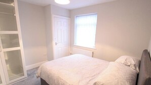 A bedroom with a bed, a wardrobe, a window with blinds, and a radiator. - Fishermans View Summa (Fleetwood)