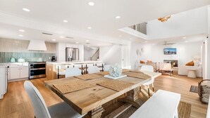 A modern kitchen with white cabinets, a wooden dining table, and a staircase leading to an upper level.