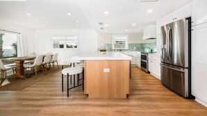 A modern kitchen with a central island, white cabinetry, and stainless steel appliances.