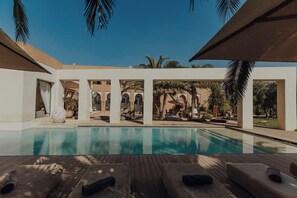 A pool area with lounge chairs and a wooden deck.