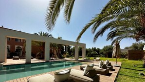 Un área junto a la piscina con sillones de descanso y una terraza de madera.