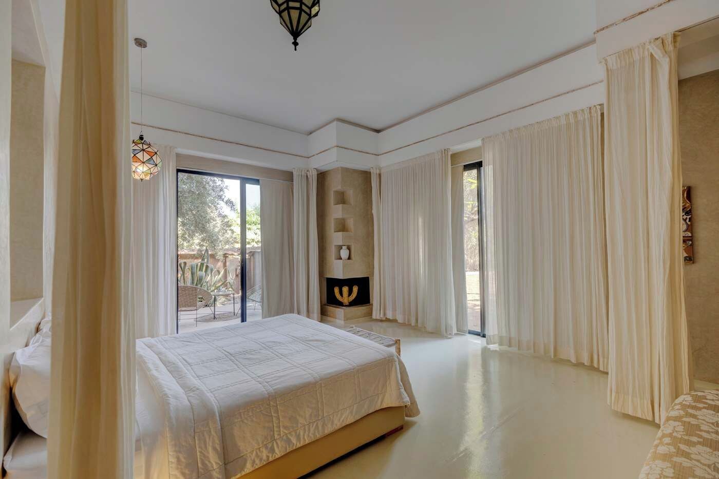 Une chambre spacieuse avec un grand lit, une cheminée et une vue sur l’extérieur.
