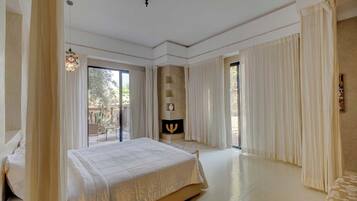 Une chambre spacieuse avec un grand lit, une cheminée et une vue sur l’extérieur.